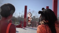 two people standing on a red structure in a park