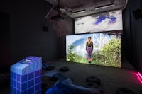 a room with a projection of a woman sitting on a bed
